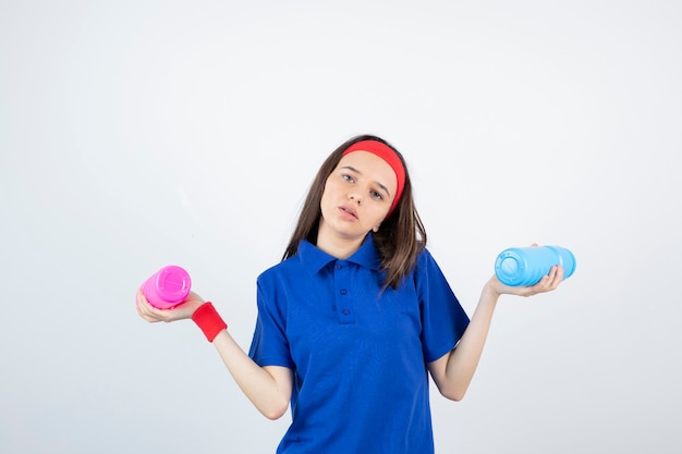 Uma jovem desportiva segurando garrafas coloridas de água.