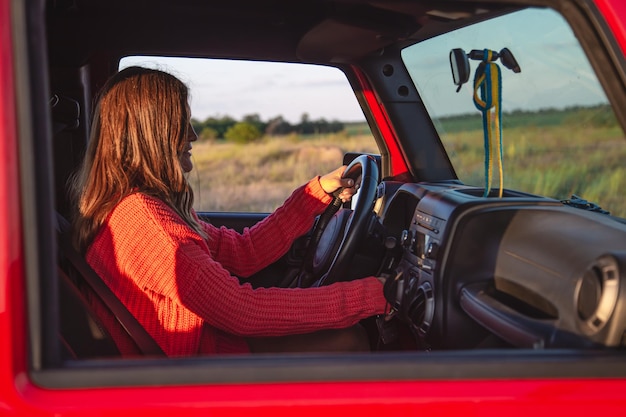 Uma jovem dirigindo um suv no campo