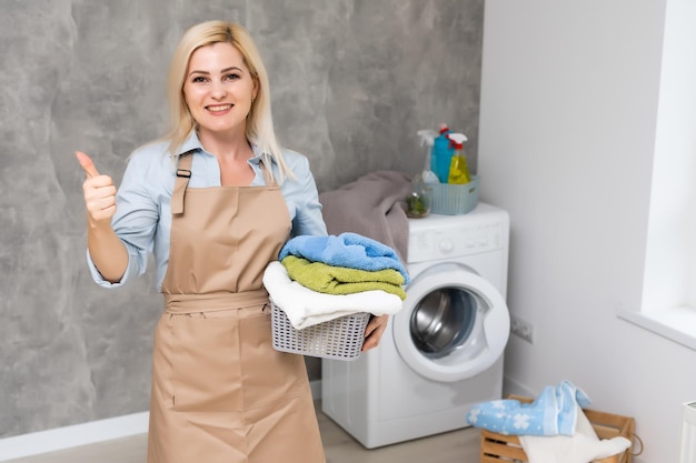 Uma jovem dona de casa com máquina de lavar e roupas. Dia de lavar.