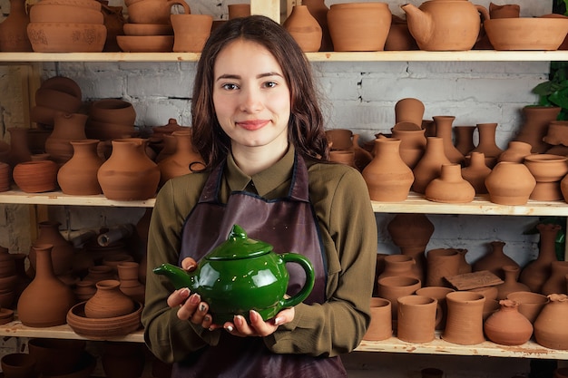Uma jovem e alegre esculpe em argila. O oleiro trabalha em uma oficina de olaria com barro. o conceito de maestria e criatividade em cerâmica.