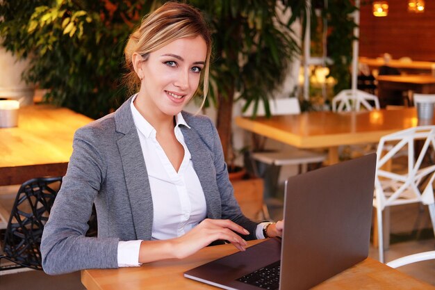 Uma jovem e atraente empresária sentada em um café com um laptop