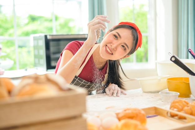 Uma jovem e bela mulher asiática está assando na cozinha, na padaria e na cafeteria