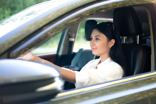 Uma jovem e linda motorista se senta ao volante de seu carro Uma senhora moderna Uma viagem uma viagem Estilo de vida