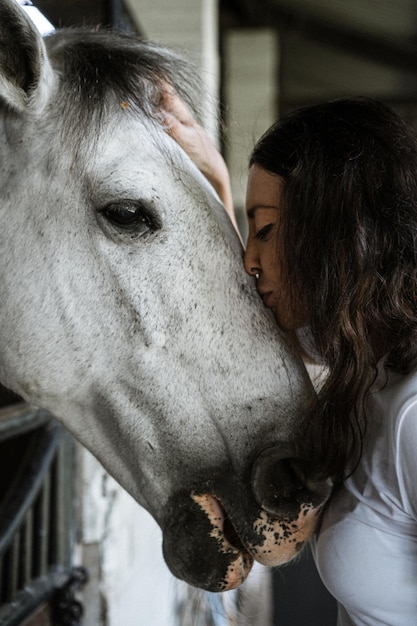 Uma jovem e um cavalo, sentimentos, cuidados, carinho, ternura, uma mulher abraça e beija um cavalo. Feche de jovem feliz abraçando seu cavalo.