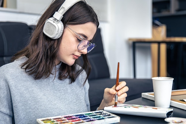 Uma jovem elegante desenha com tintas no interior de casa