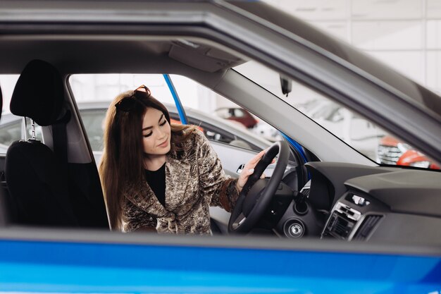 Uma jovem elegante está escolhendo um carro novo em uma loja de carros