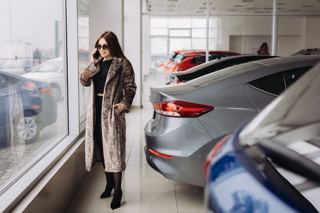 Uma jovem elegante está escolhendo um carro novo em uma loja de carros