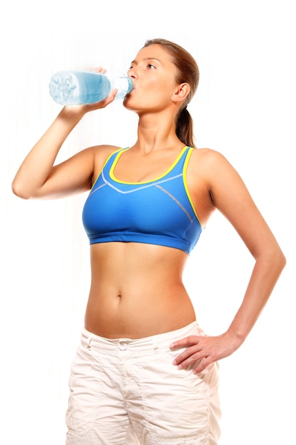 Uma jovem em forma bebendo água de uma garrafa