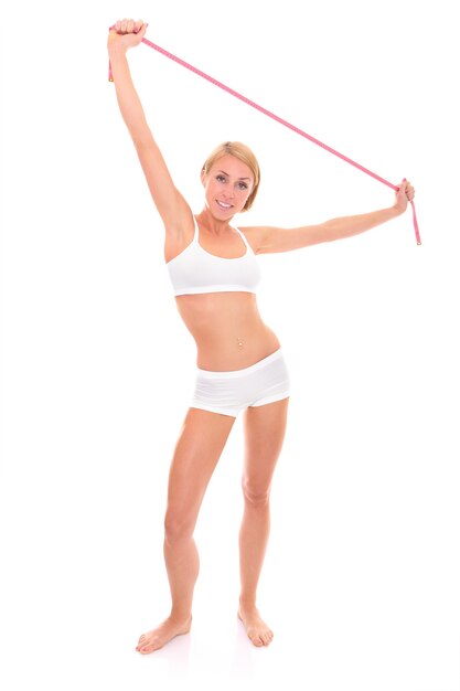 uma jovem em forma de mulher feliz em pé com uma fita métrica sobre o branco