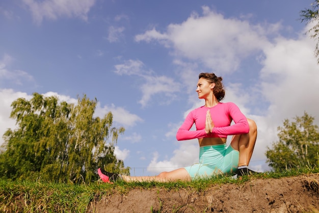 Uma jovem em roupas brilhantes pratica esportes em um parque na natureza