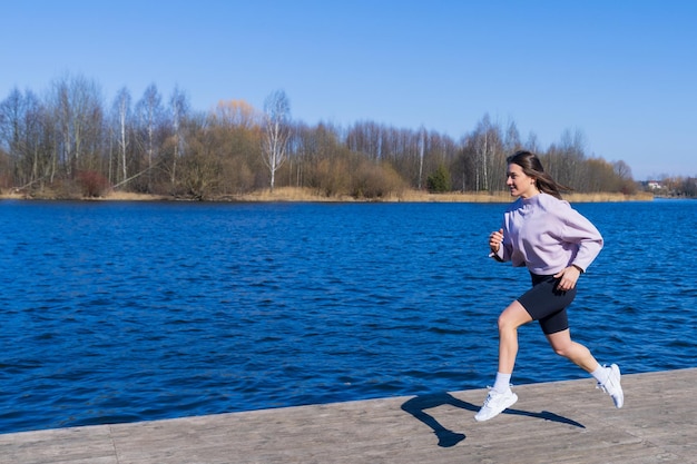 Uma jovem em um agasalho corre ao longo do aterro