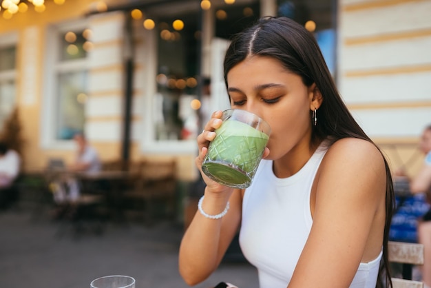 Uma jovem em um café bebe um latte de gelo de bebida verde