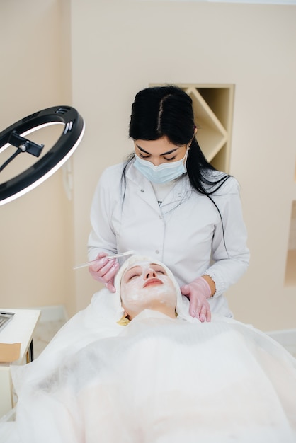 Uma jovem em um consultório de cosmetologia está passando por procedimentos de rejuvenescimento da pele facial. cosmetologia.