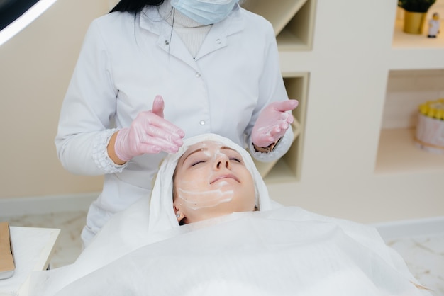 Uma jovem em um consultório de cosmetologia está passando por procedimentos de rejuvenescimento da pele facial. Cosmetologia.