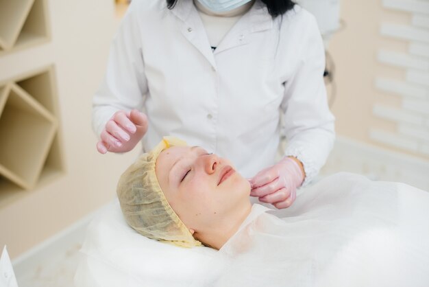 Uma jovem em um consultório de cosmetologia está passando por procedimentos de rejuvenescimento da pele facial. Cosmetology.