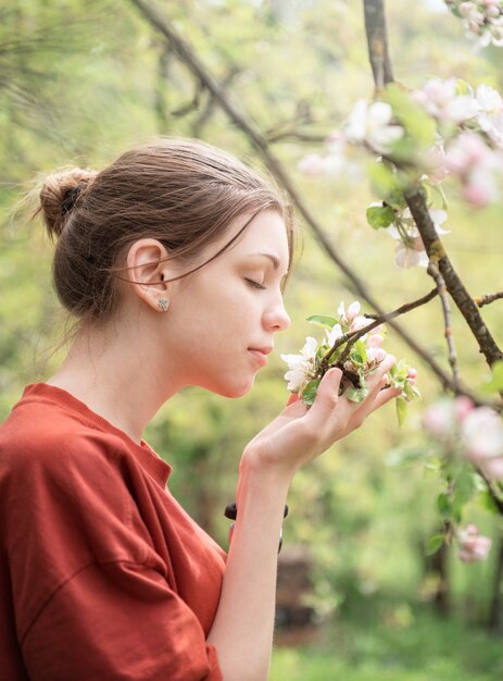 Uma jovem em um jardim florido olha para árvores floridas