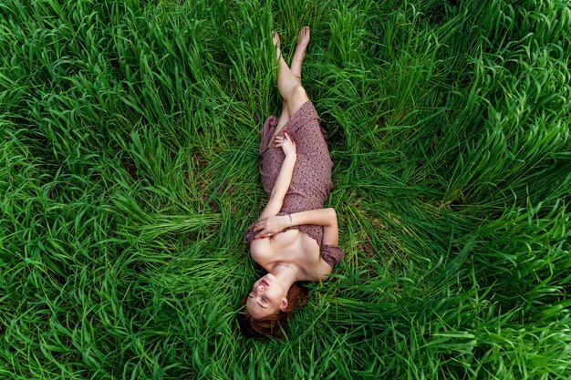Uma jovem em um lindo vestido está na grama verde