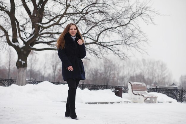 Uma jovem em um parque de inverno em uma caminhada férias de Natal na floresta de inverno A garota gosta de inverno no parque