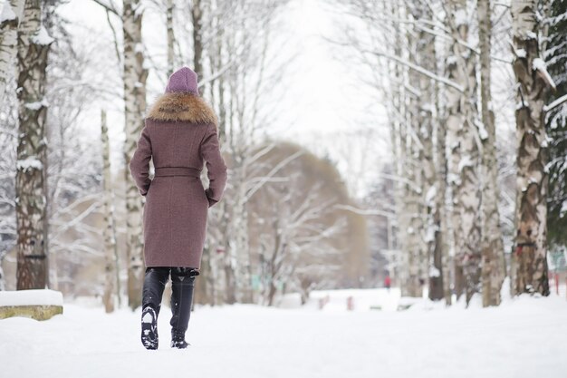 Uma jovem em um parque de inverno em uma caminhada. Férias de Natal na floresta de inverno. Garota gosta de inverno no parque.