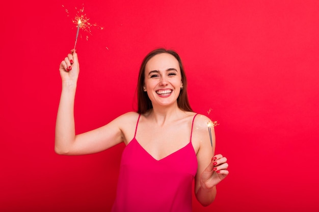 Uma jovem em um vestido rosa de grife segura estrelinhas em um fundo vermelho