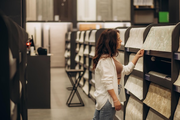 Uma jovem em uma loja escolhe papel de parede para sua casa Conceito de reparo e compras Foto de alta qualidade