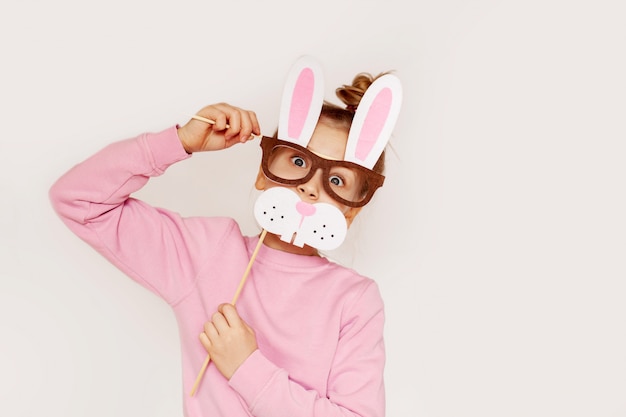Uma jovem em uma máscara de óculos com orelhas de coelho em um suéter rosa
