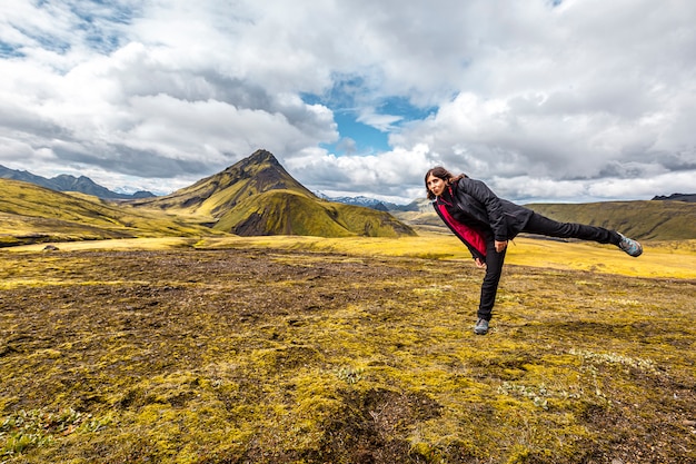 Uma jovem em uma montanha verde na caminhada de 54 km de landmannalaugar, islândia