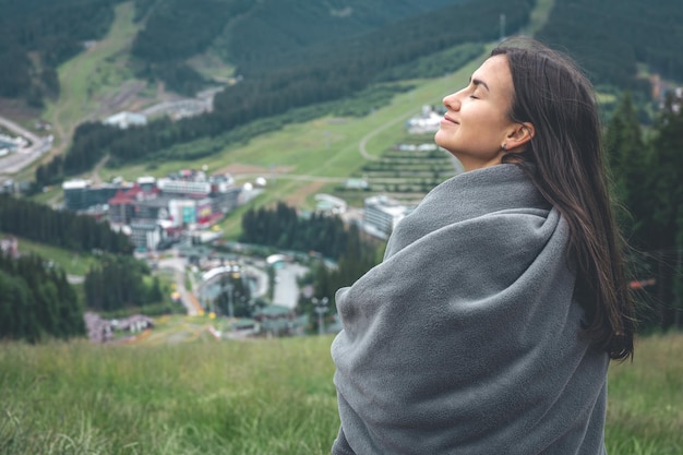 Uma jovem embrulhada em um cobertor nas montanhas
