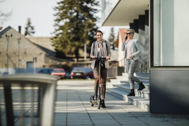 Uma jovem empresária andando de scooter elétrica a caminho do trabalho.