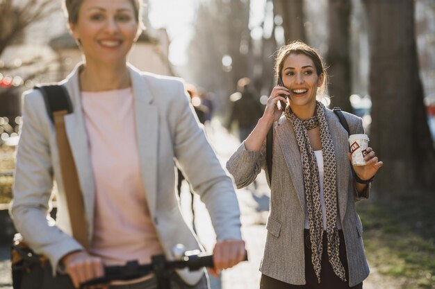 Uma jovem empresária falando em um smartphone enquanto vai trabalhar pela cidade.