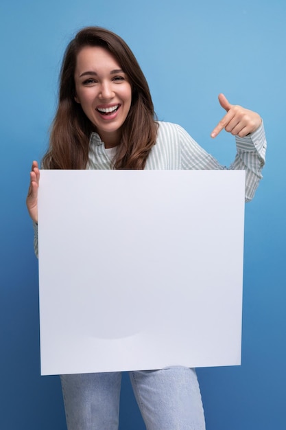 Uma jovem empresária muito morena de camisa demonstra um pôster branco com uma maquete