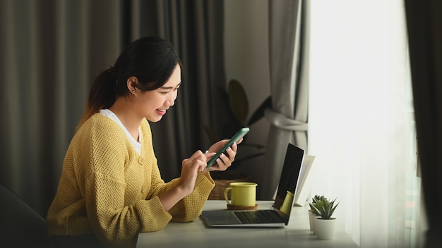 Uma jovem empresária sorridente, sentada à mesa em seu escritório em casa