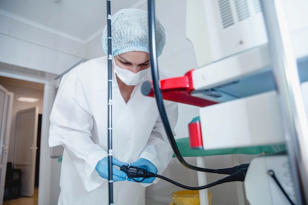 Uma jovem endoscopista com uma touca de proteção branca e luvas prepara o equipamento para o trabalho