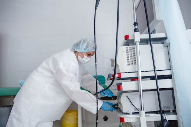 Foto uma jovem endoscopista com uma touca de proteção branca e luvas prepara o equipamento para o trabalho