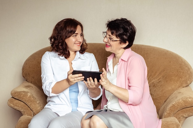 Uma jovem ensina sua mãe 60 anos a se comunicar usando chamadas de vídeo em um tablet.