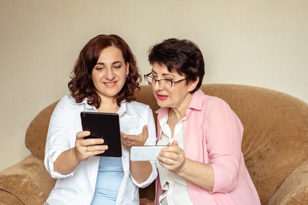 Uma jovem ensina sua mãe 60 anos a se comunicar usando chamadas de vídeo em um tablet.