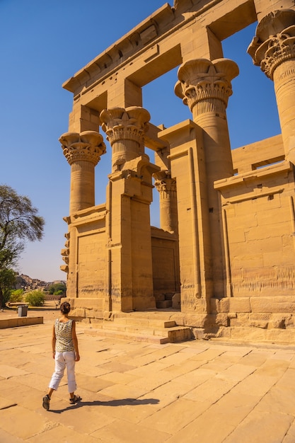 Uma jovem entrando no Templo de Philae com suas belas colunas, uma construção greco-romana, um templo dedicado a Ísis, deusa do amor. Aswan. egípcio