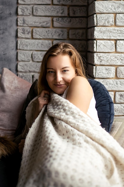 Uma jovem envolve-se num mole cobertor branco o seu olhar fixo na câmara um momento de tranquilidade e relaxamento capturado simbolizando a serenidade