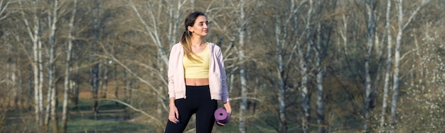 Uma jovem esbelta atlética em roupas esportivas realiza um conjunto de exercícios Fitness e estilo de vida saudável no contexto das colinas verdes de pastagem de primavera
