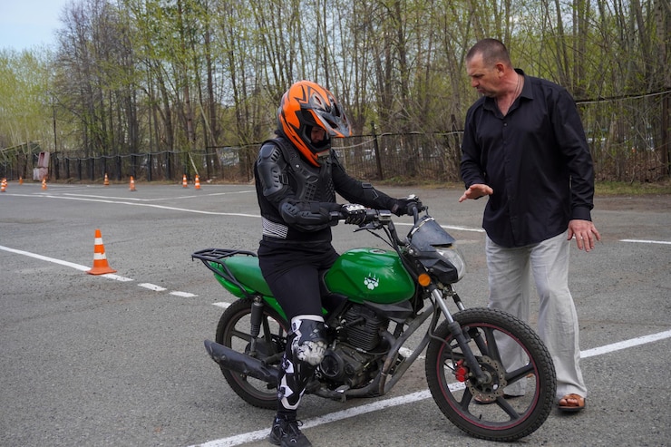 Foto uma jovem está aprendendo a andar de moto em uma escola de motocicleta ela é ensinada por um professor