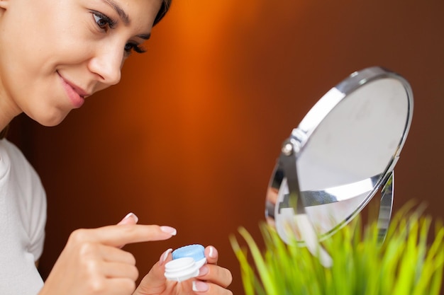 Uma jovem está colocando lentes de contato na frente do espelho