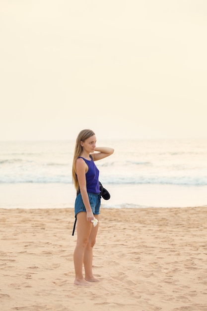 Uma jovem está de pé na praia perto do oceano