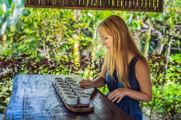 Uma jovem está degustando diferentes tipos de café e chá, incluindo o café Luwak.