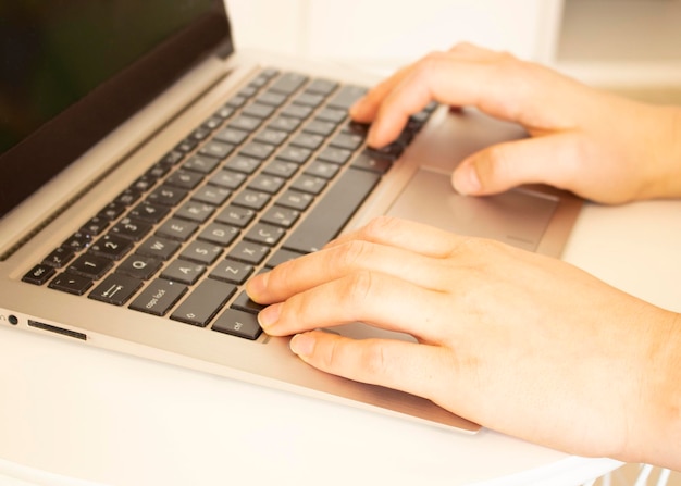 Uma jovem está em uma sala e trabalha em um laptop