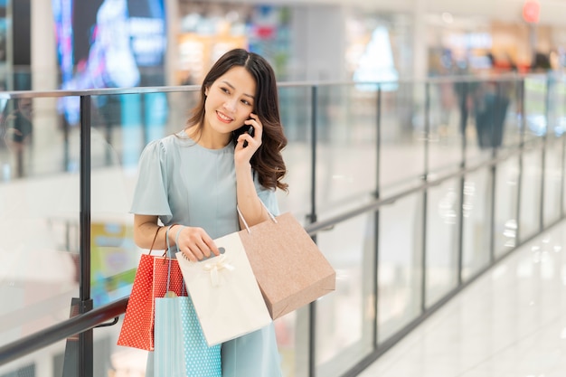 Uma jovem está fazendo compras e usando o telefone no shopping