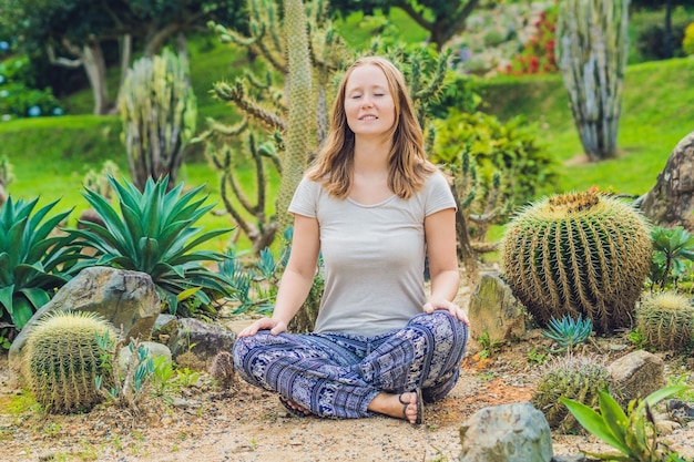 Uma jovem está meditando entre um cacto