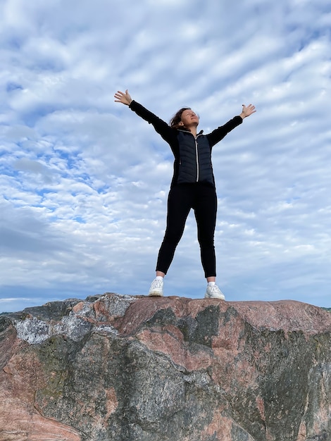 Foto uma jovem está no topo de uma montanha com os braços levantados