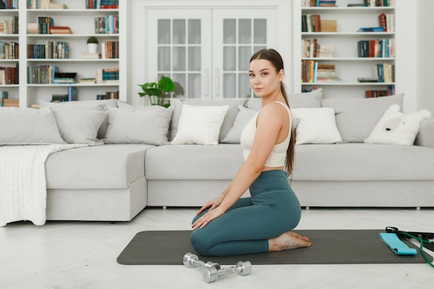 Uma jovem está se preparando para praticar esportes sentada no chão em uma sala de estar brilhante