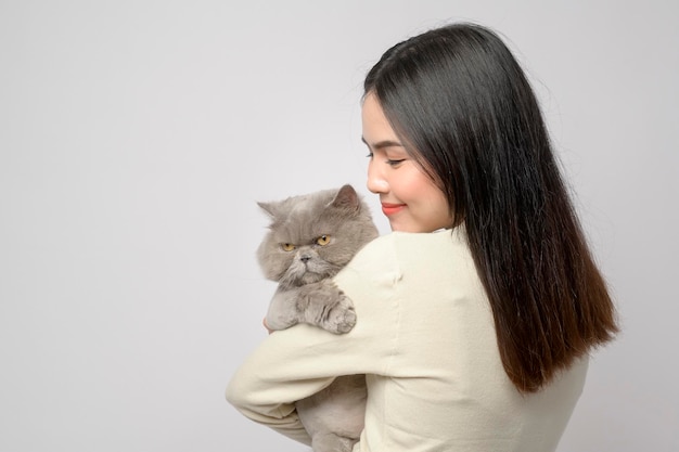 Uma jovem está segurando um lindo gato brincando com gato em estúdio em fundo branco