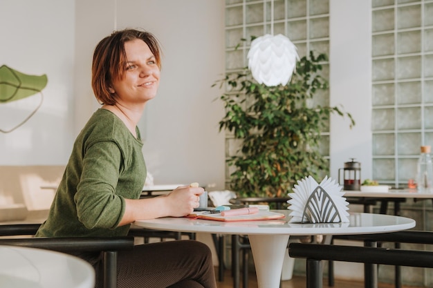 Foto uma jovem está sentada em uma mesa em um café